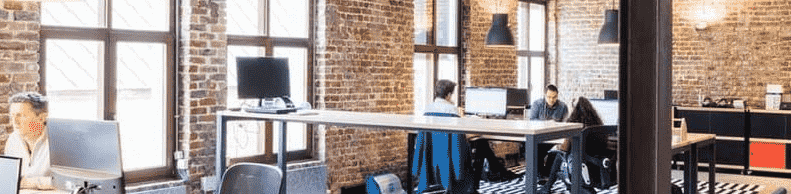 a room with a brick wall and a large desk with computers